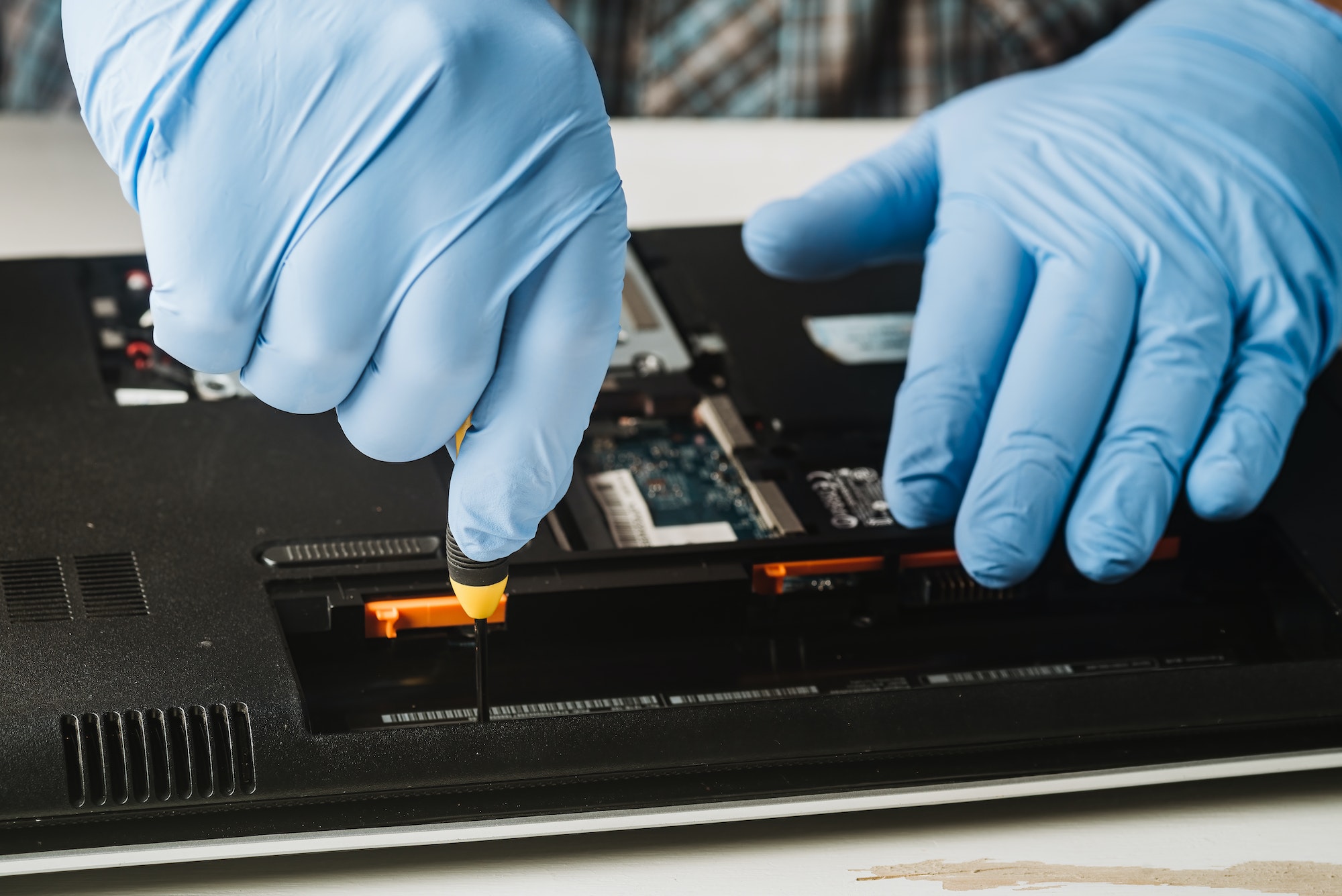 Man using a screwdriver to disassemble a computer for maintenance